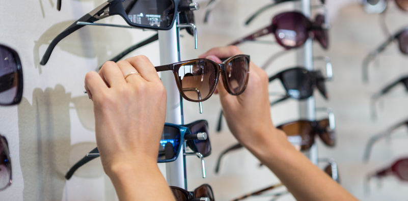 A person selecting sunglasses from display at the opticians.