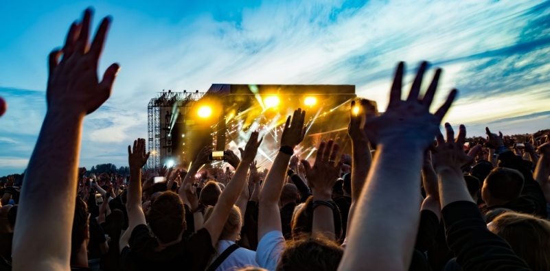 A crowd of people with raised hands enjoying a live outdoor festival.