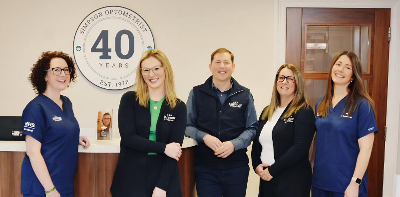 A photo of the team at Simpson Optometrists in front of their reception desk