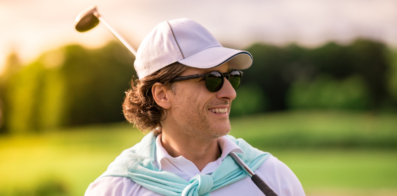 A well-dressed man at the golf course wearing a pair of sunglasses